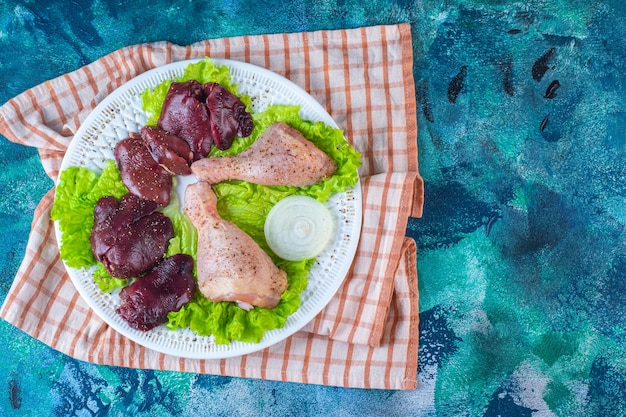 Fígado de frango, folhas de alface e coxinha de frango em um prato sobre o pano de prato