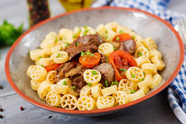 Fígado de frango frito com tomate e guarnição de macarrão