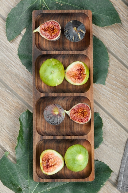 Figos com sementes vermelhas em uma bandeja de madeira.