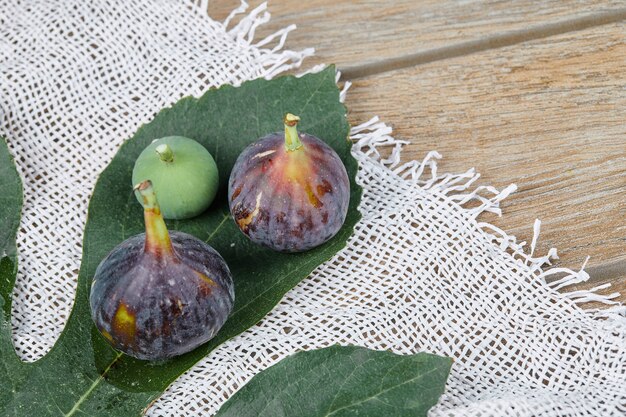 Figos maduros com folhas e uma toalha de mesa branca na mesa de madeira.