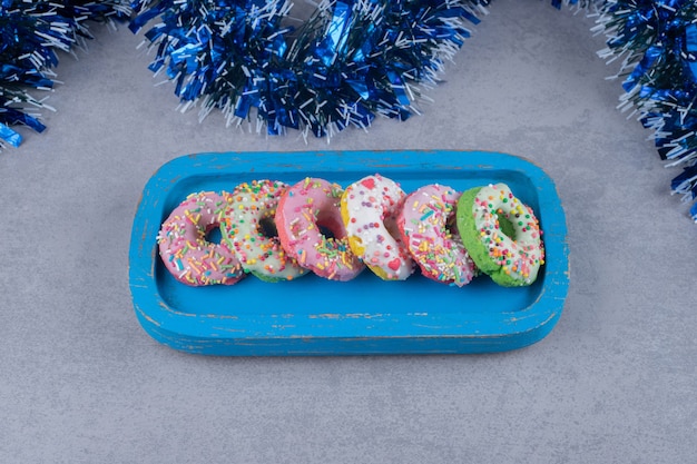 Fila de donuts em uma bandeja azul na superfície de mármore