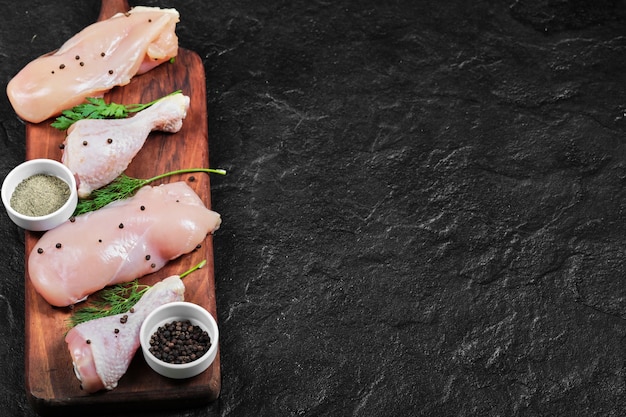 Foto grátis filé de frango cru e coxas em prato de madeira