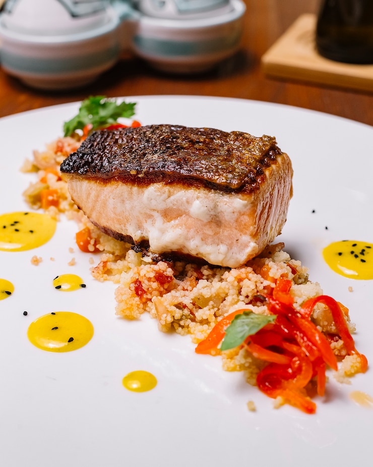 Foto grátis filé de peixe grelhado servido em cima da salada de cuscuz com pimentão vertical