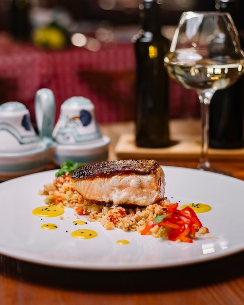 Foto grátis filé de peixe grelhado servido em cima da salada de cuscuz com pimentão