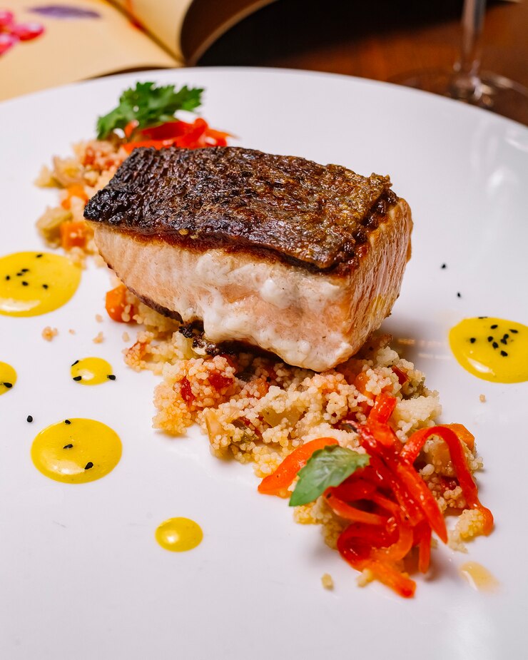 Foto grátis filé de peixe grelhado servido em cima da salada de cuscuz com pimentão