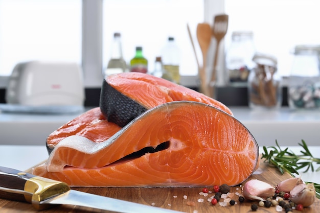 Filé de salmão cru fresco com ingredientes em uma tábua de cortar na cozinha