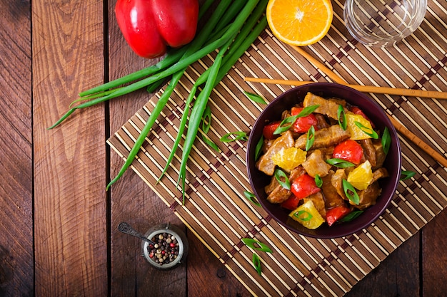 Filé de vitela - frite com laranjas e páprica em molho agridoce em uma mesa de madeira. postura plana. vista do topo