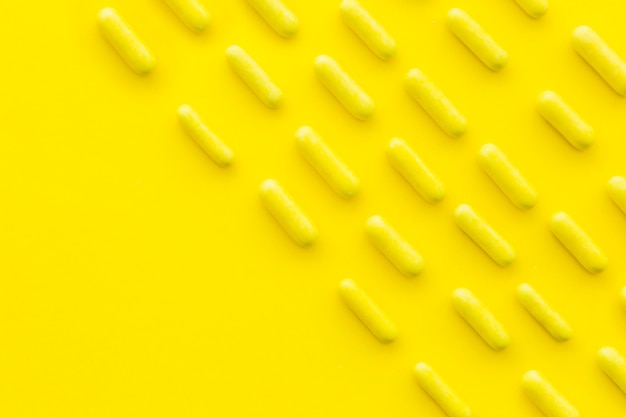 Fileiras de cápsulas de doces em pano de fundo amarelo