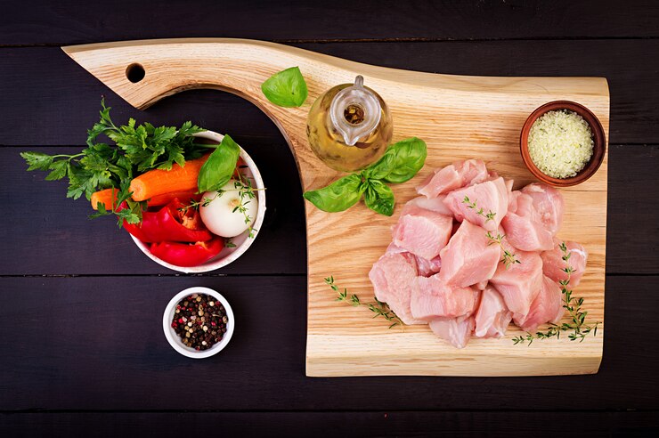 Foto grátis filetes de peito de frango cru na tábua de madeira com ervas e especiarias. vista do topo