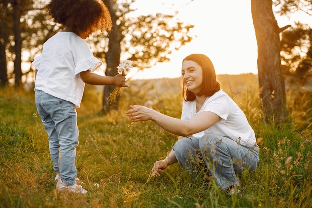 Filha afro-americana dando uma flor para sua mãe caucasiana