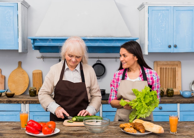 Filha ajudando sua mãe para preparar vegetais na cozinha