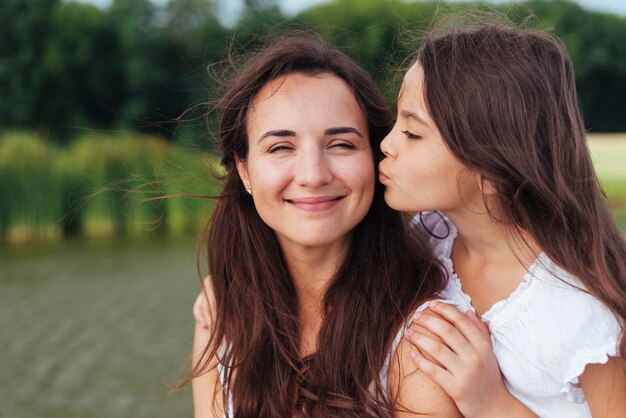 Filha, beijando, feliz, mãe, por, a, lago