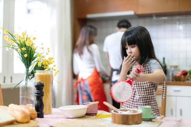 Filha bonita aprende a cozinhar com o pai na cozinha