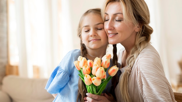 Filha dando buquê de flores para a mãe como presente