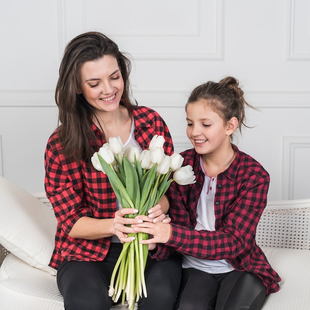 Foto grátis filha dando flores tulipa para a mãe no sofá