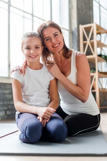 Filha e mãe posando em tapetes de ioga