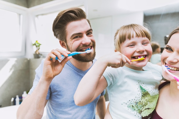 Filha e pais escovando os dentes