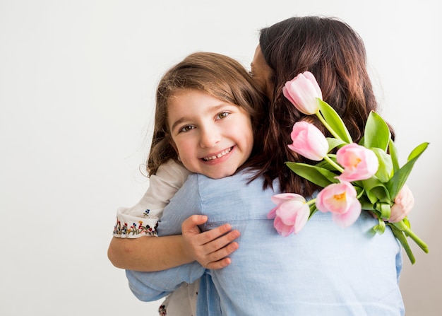 Filha feliz com tulipas abraçando a mãe