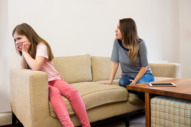 Filha ignorando sua mãe após uma discussão na sala de estar