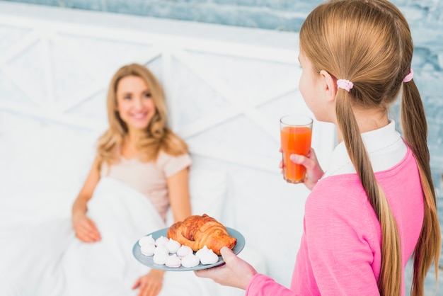 Filha, segurando, croissant, e, suco, para, mãe