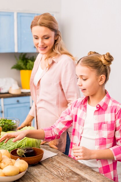 Filha sorridente ajudando a mãe na cozinha