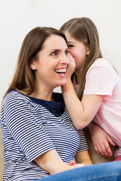 Filha sussurrando em seu ouvido mães