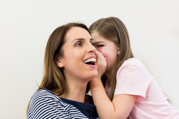 Filha sussurrando em seu ouvido mães