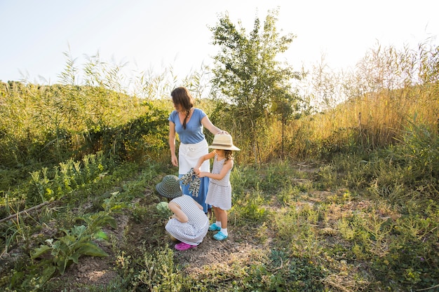 Filhas colhendo legumes com a mãe no campo