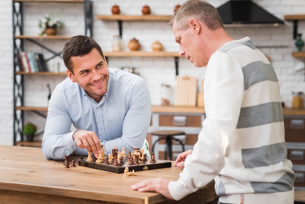 Foto grátis filho ganhando um jogo de xadrez na frente de seu pai