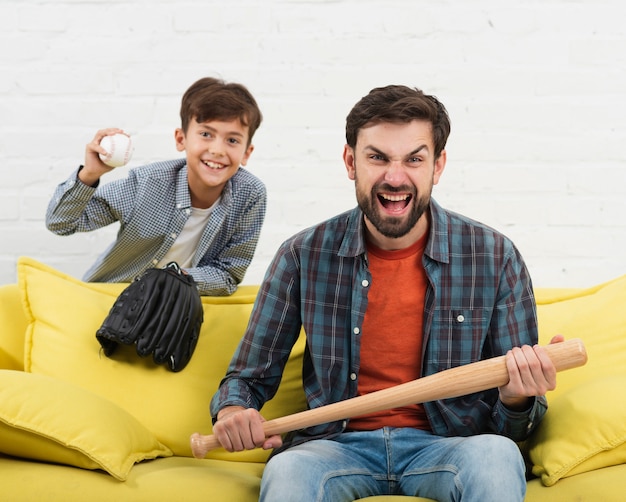 Foto grátis filho, segurando uma bola e pai um taco de beisebol