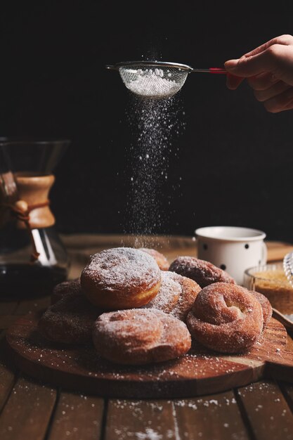 Filmagem vertical de deliciosos donuts cobra polvilhados com açúcar de confeiteiro e café chemex