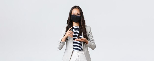 Finanças de negócios e emprego covid19 prevenindo vírus e conceito de distanciamento social Empresária asiática em máscara facial aplica desinfetante para as mãos para lavar as mãos durante o trabalho