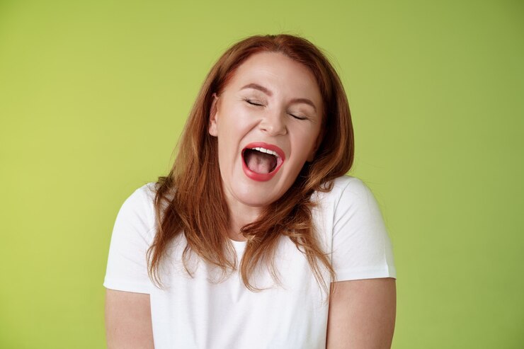 Foto grátis fins de semana preguiçosos finalmente hora de dormir alegre ruiva mulher de meia-idade bocejando satisfeito feche os olhos com sono acorde de manhã cedo quero tirar uma soneca ficar parede verde assistindo filme chato