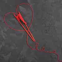 Foto grátis fio de lã vermelho e agulhas na ardósia
