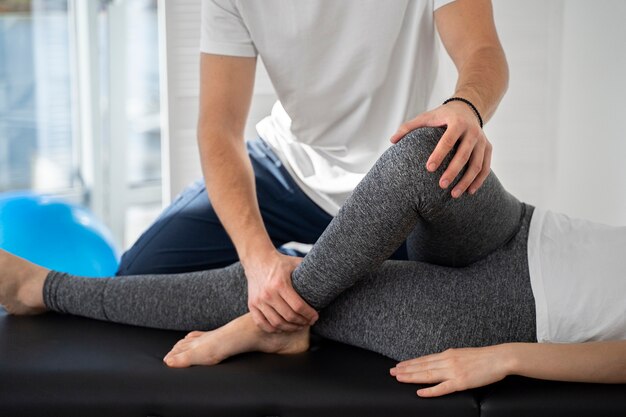 Fisioterapeuta ajudando a perna do paciente de perto
