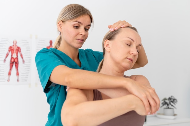 Foto grátis fisioterapeuta ajudando um paciente em sua clínica