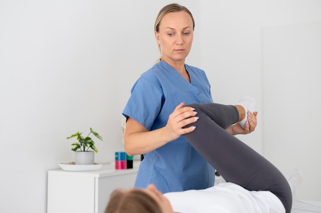 Foto grátis fisioterapeuta ajudando uma jovem paciente em sua clínica