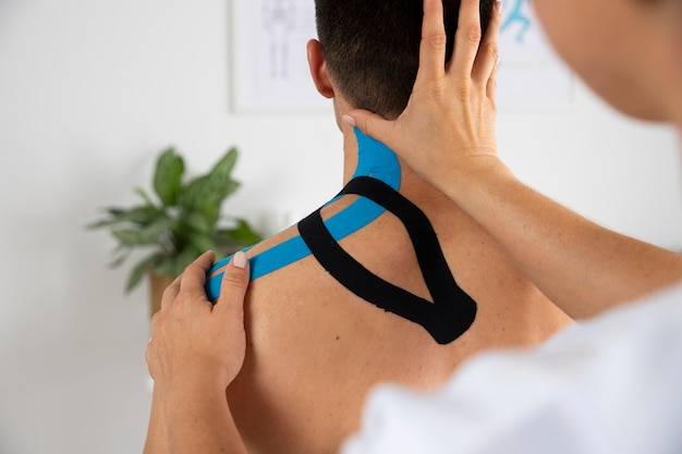 Fisioterapeuta aplicando bandagem médica elástica em paciente do sexo masculino