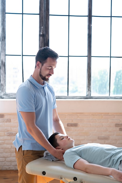 Foto grátis fisioterapeuta com dose média massageando o pescoço