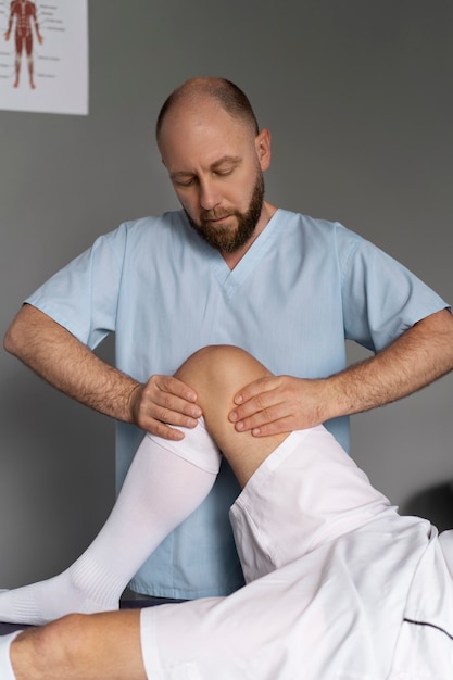 Foto grátis fisioterapeuta de vista frontal, ajudando o paciente