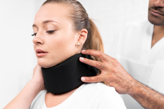 Foto grátis fisioterapeuta masculino colocando colar cervical na mulher