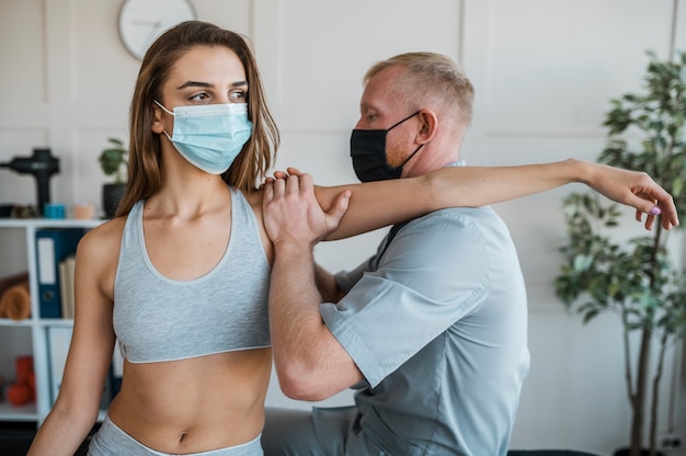 Foto grátis fisioterapeuta masculino usando máscara médica durante uma sessão de terapia