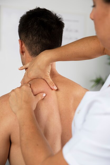 Fisioterapeuta realizando massagem terapêutica a um cliente masculino
