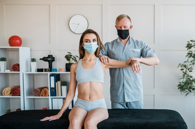 Fisioterapeuta usando máscara médica durante uma sessão de terapia com uma mulher