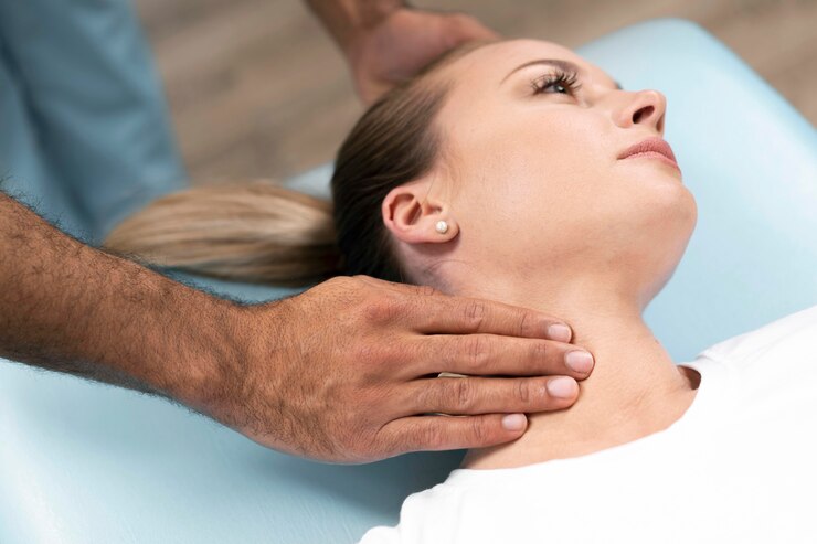 Foto grátis fisioterapeuta verificando o pescoço da mulher enquanto está sentado na cama