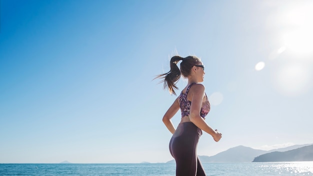 Fit girl correndo na praia