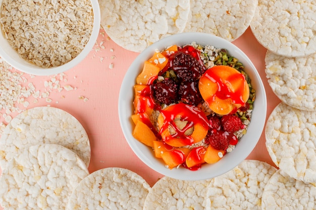 Flocos de aveia em tigelas com nozes, frutas, damasco, geléia, bolos de arroz