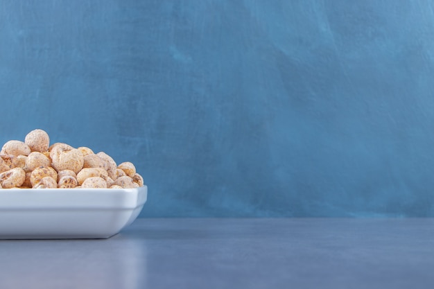 Flocos de milho doces com muesli em uma tigela, na mesa de mármore.