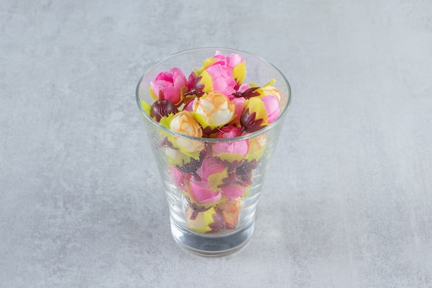 Flor e vidro coloridos, na mesa branca.