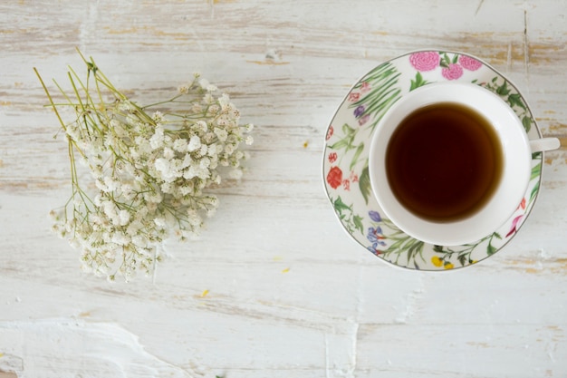 Flores ao lado de uma chávena de chá